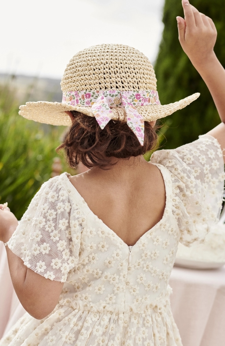 Mädchen von hinten in einem weißen Kleid und festlichem Hut